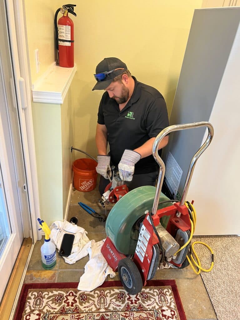 Ready Rooter technician servicing a water heater in a hallway utility closet