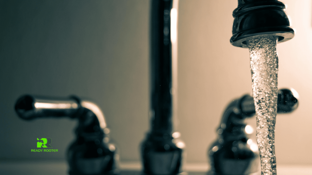 Water running from a faucet against a dark background