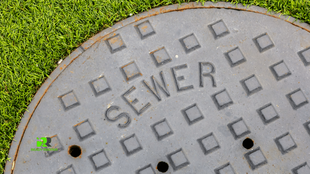 Cast iron sewer manhole cover set in a green lawn