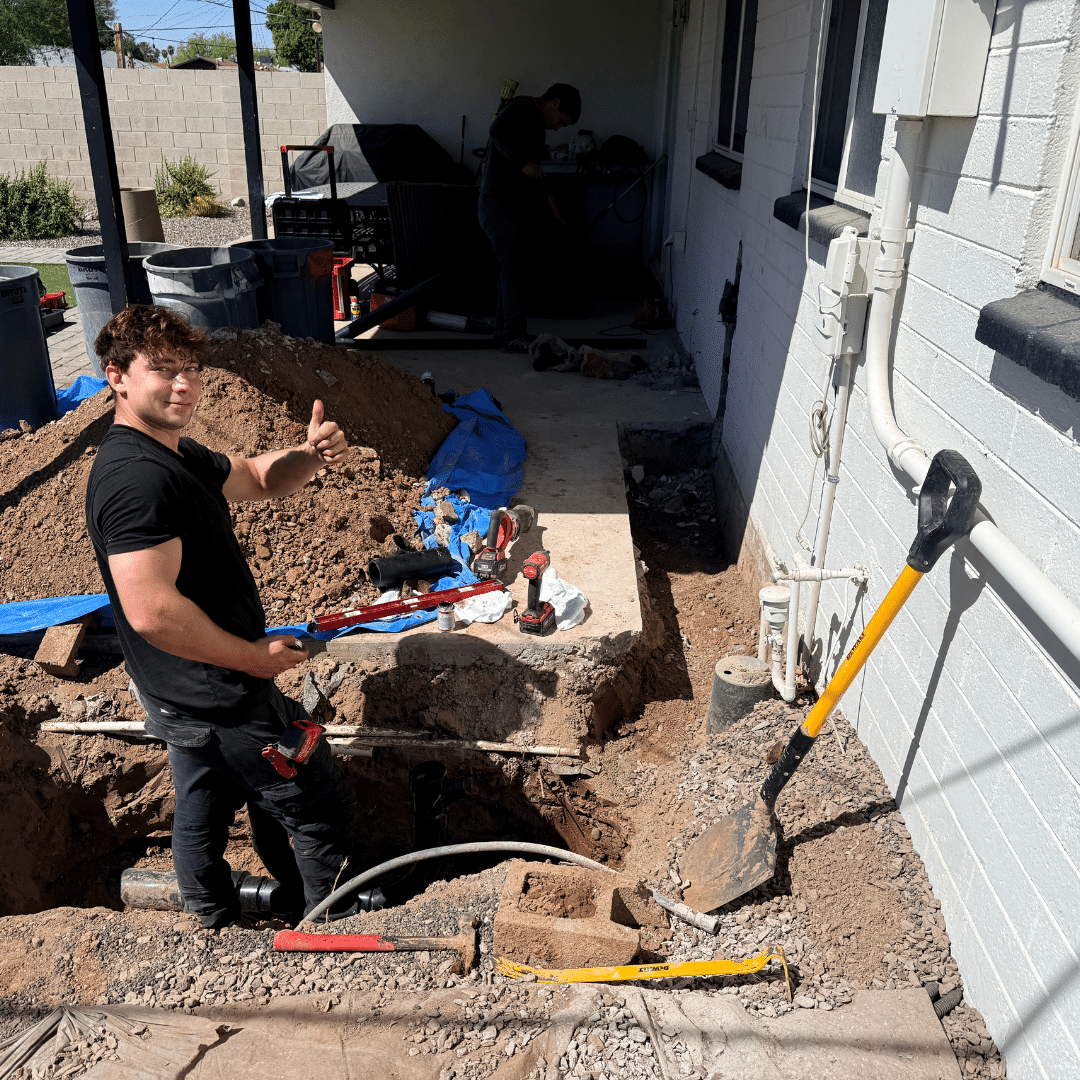 Ready Rooter technician working in an excavated hole beside a home during a repipe