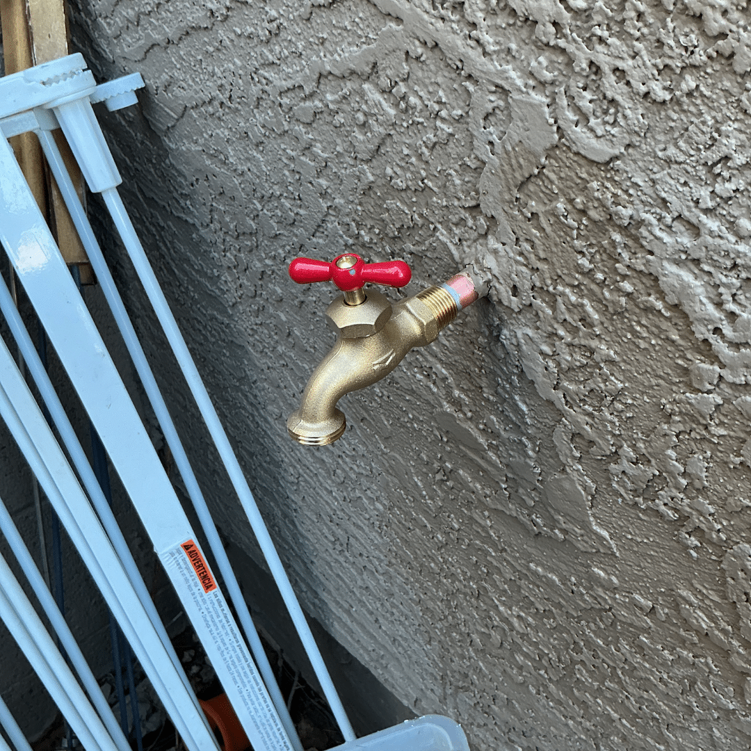 Newly installed outdoor spigot on a stucco wall with fresh supply lines