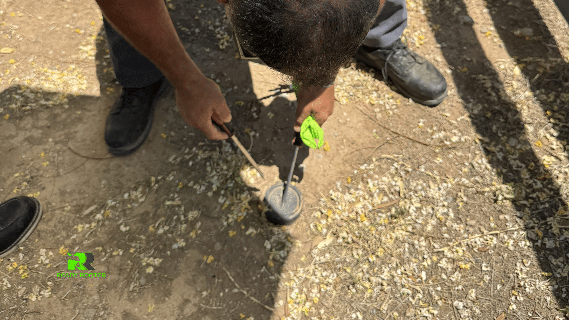 Technician digging into gravel to expose a buried water line